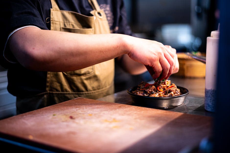 Koch garniert ein Gericht in der Profiküche